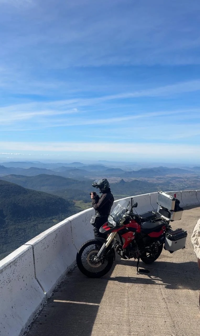 Motocicleta estacionada em um mirante com montanhas ao fundo.