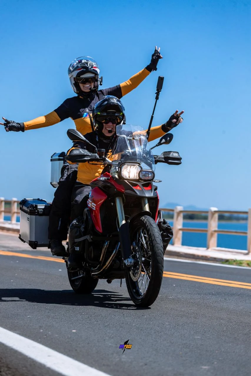 Motociclistas viajando por uma ponte sob céu azul