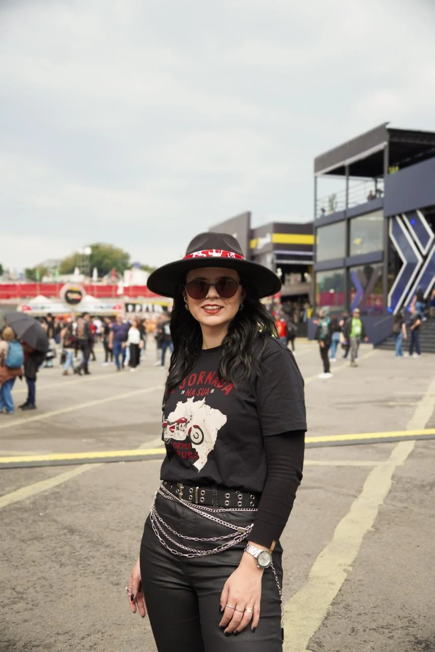 Retrato de Carol com seu chapéu e óculos escuros em um evento de motociclismo.